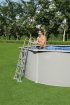 Mann im Pool mit Metallrahmen und Leiter, draußen im Garten.
