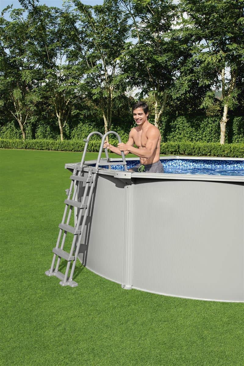 Mann im Pool mit Metallrahmen und Leiter, draußen im Garten.
