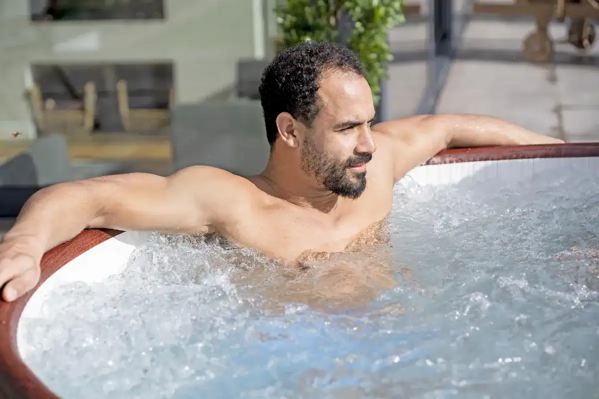 Ein Mann entspannt sich im aufblasbaren Whirlpool mit AirJet-Massagefunktion.