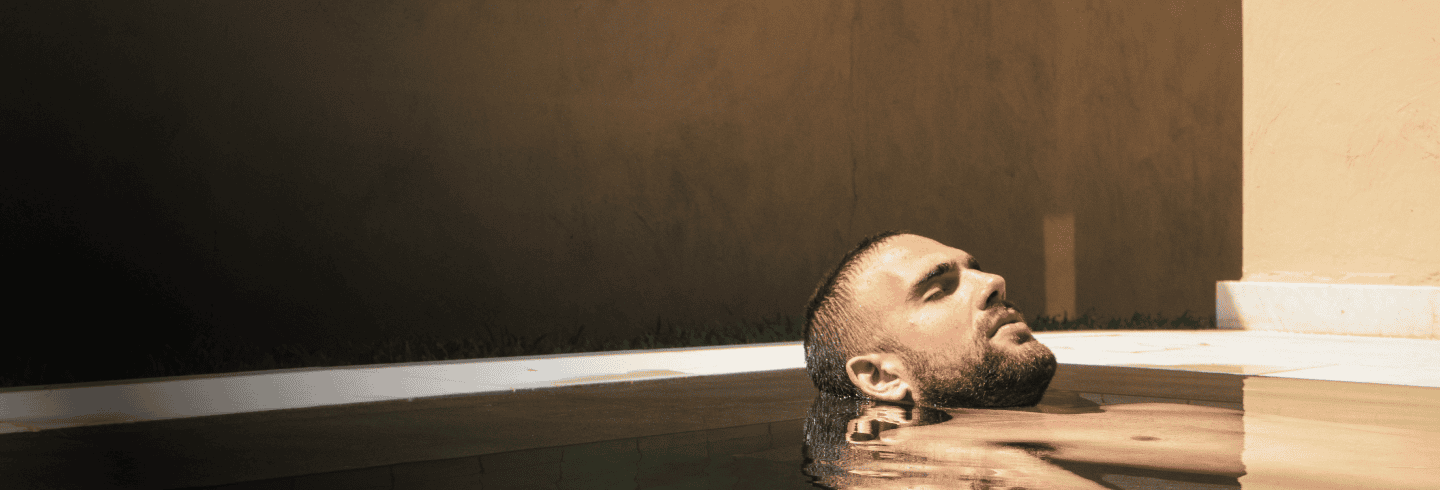 Gesicht und Schultern eines Mannes, der sich in einem Pool entspannt, mit einer ruhigen und entspannten Atmosphäre.