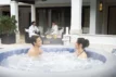 Zwei Personen genießen den Lay-Z Spa Santorini HydroJet Pro WiFi im Garten.