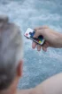 Mann bedient die Spa-Steuerung über die Fernbedienung im Wasser.