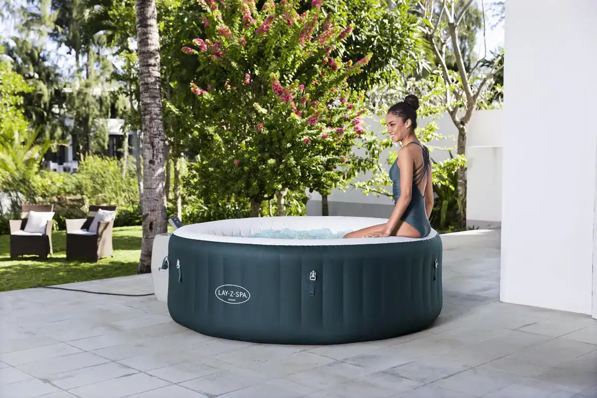 Aufblasbarer Whirlpool im Garten mit Frau, die im warmen Wasser entspannt.