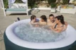 Schwimmspa mit vier Personen, die im Garten genießen.