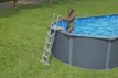 Ein Erwachsener steigt aus einem aufblasbaren Pool in einem grünen Garten.