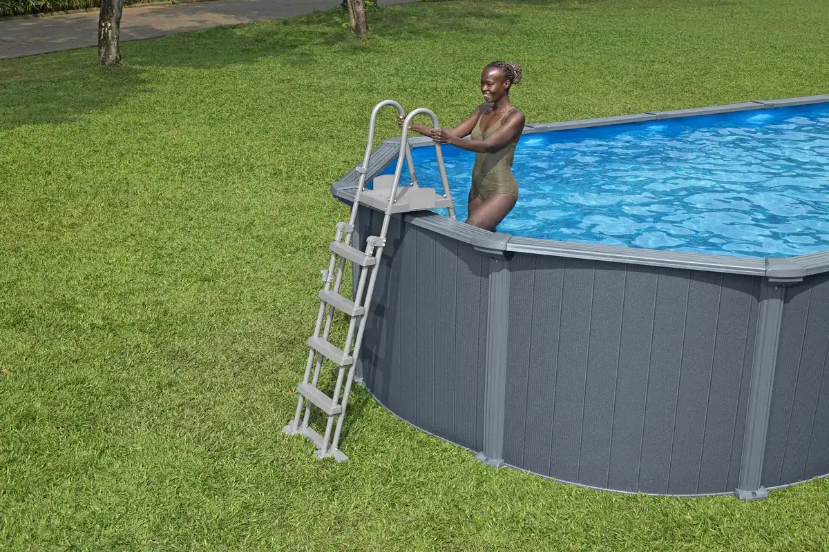 Ein Erwachsener steigt aus einem aufblasbaren Pool in einem grünen Garten.