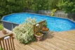 Schwimmteich im Garten mit Holzterrasse, umgeben von Grün und Pflanzen, ideal für sommerliche Entspannung.