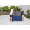 Zwei Personen bauen einen aufblasbaren Pool auf einer Terrasse mit Pflanzen und Holzzaun auf.