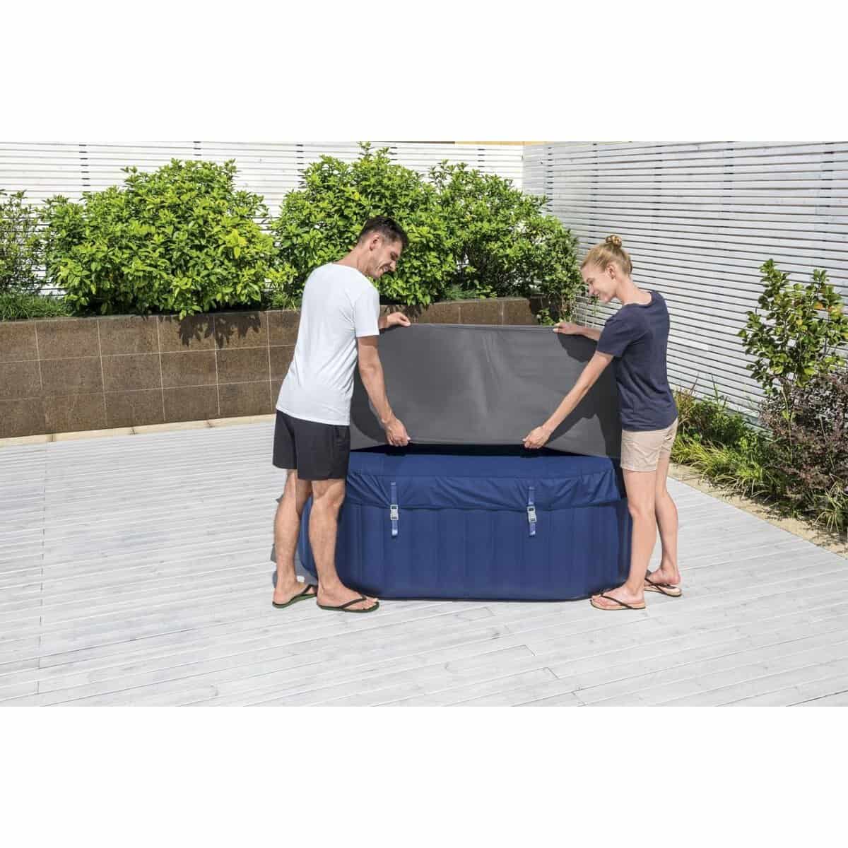 Zwei Personen bauen einen aufblasbaren Pool auf einer Terrasse mit Pflanzen und Holzzaun auf.